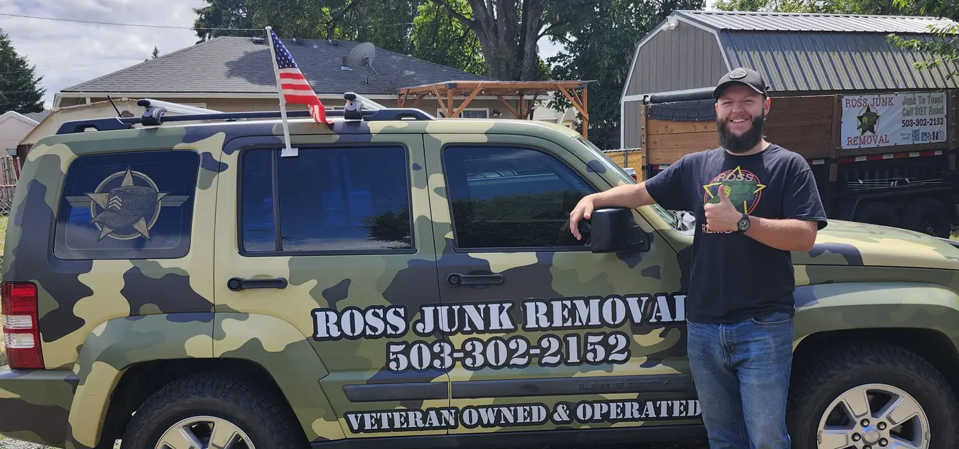 Veteran owner of Ross Junk Removal standing beside the camo-wrapped company Jeep in Salem, Oregon