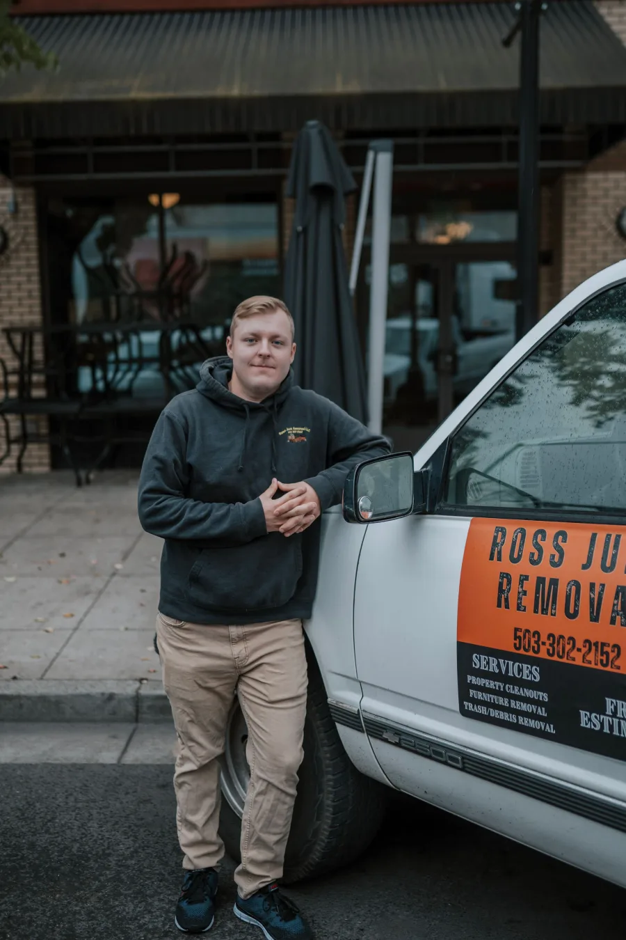 Founder of Ross Junk Removal leaning on the company's branded truck in Salem, Oregon