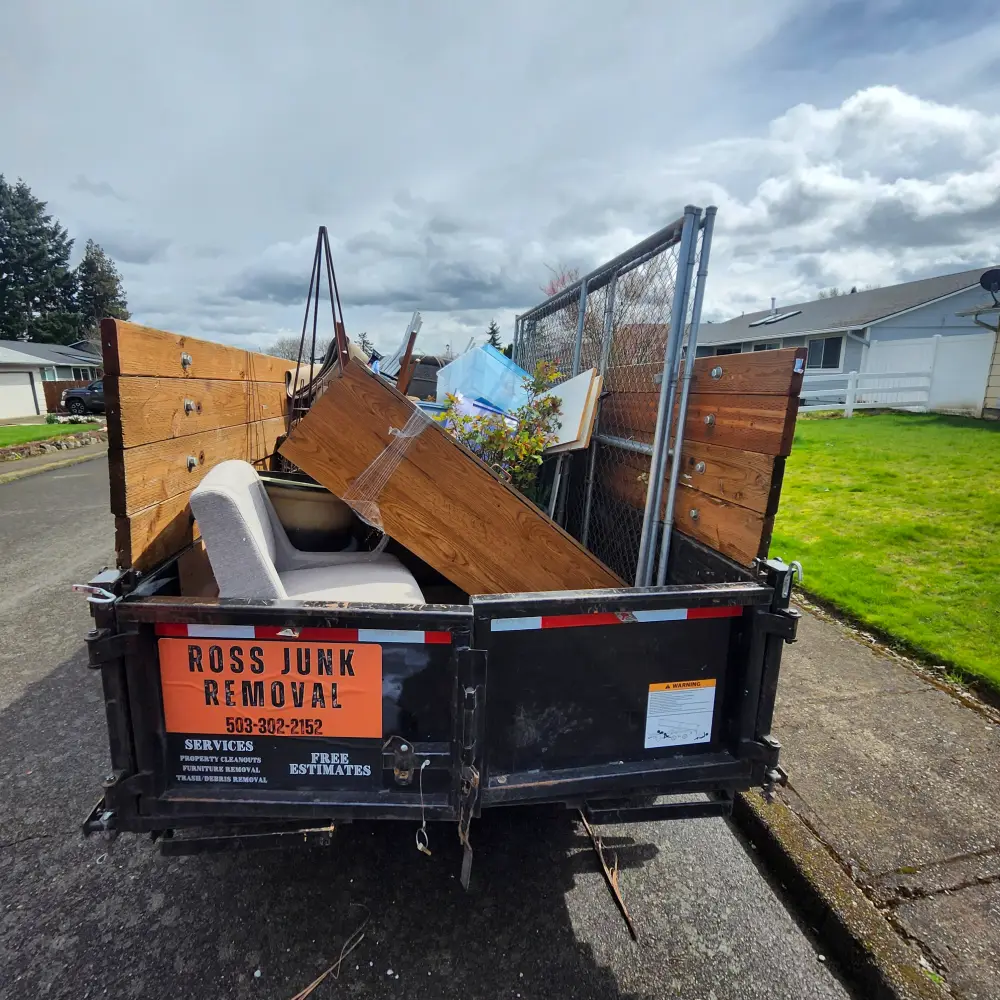 Dump trailer filled with an old recliner, wood, and fencing from a South Salem property