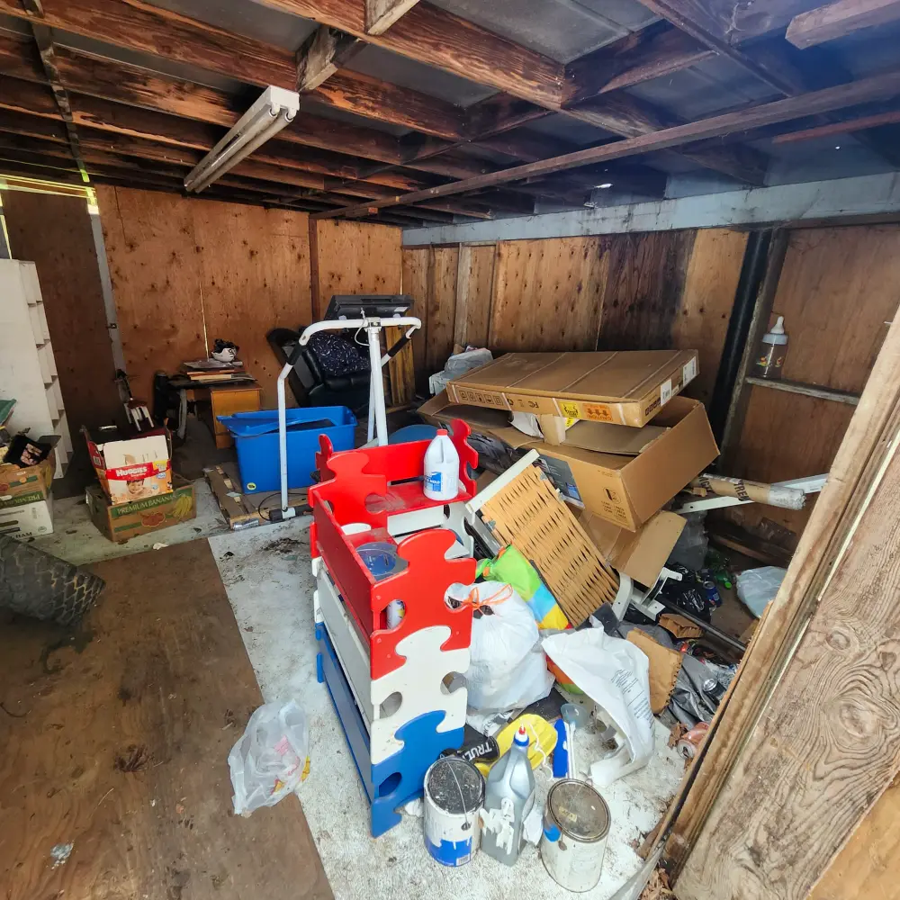Cluttered garage packed with boxes, toys, and paint before a Hayesville garage cleanout