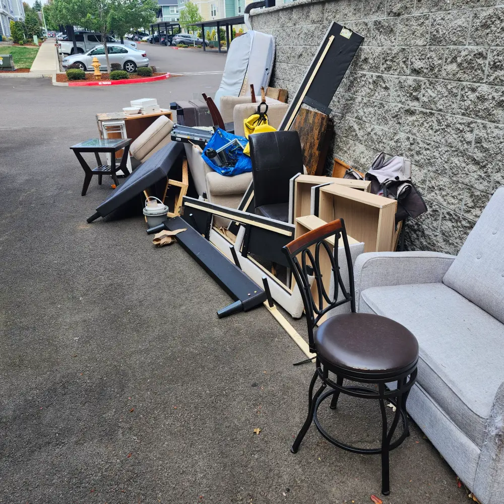 Chairs, stools, and tables staged for furniture removal from a Keizer driveway