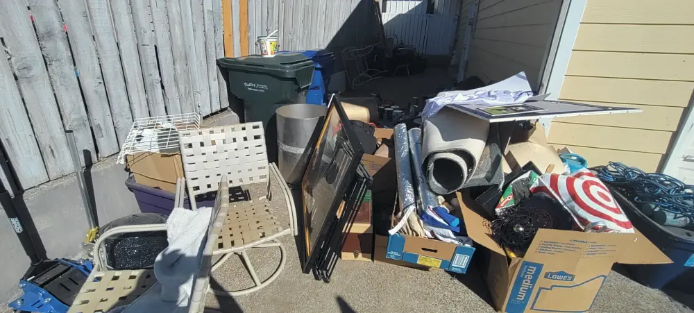 Patio furniture, old TV, and bins staged for junk removal at a Salem, OR home